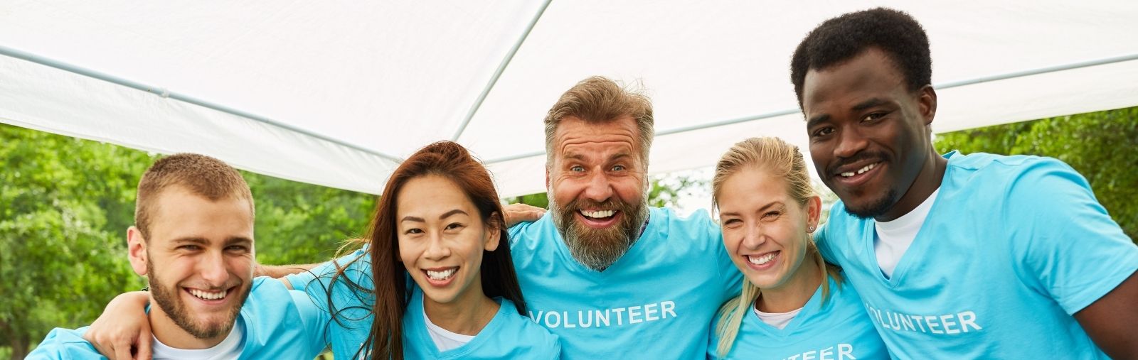 A group of people in "volunteer" shirts with their arms around each other
