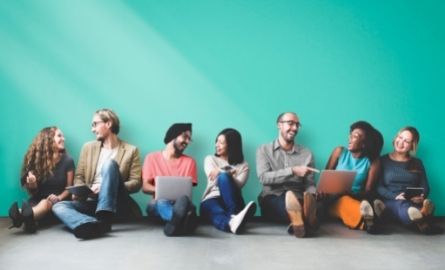 Pairs of people talking and sitting in front of a teal wall
