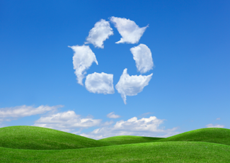 Hilly grass and blue sky with clouds in shape of recyling.