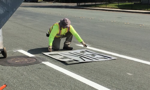photo of construction worker placing bike lane marking stencil on roadway