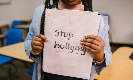 child holding sign with heart saying stop bullying