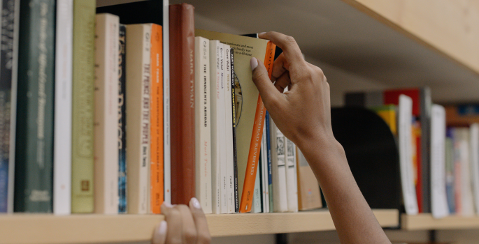 hand picking a book from a bookshelf