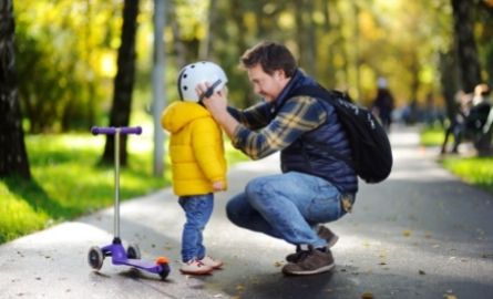 A man putting a helmet on a child