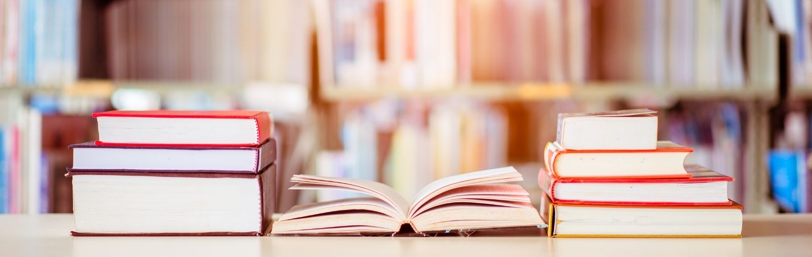 An open book on a table between two stacks of books