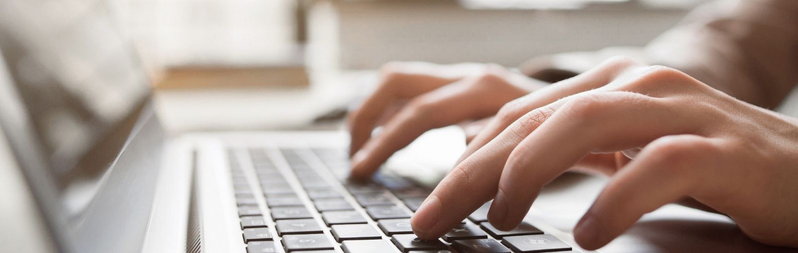 A close-up of a person's hands typing on a laptop