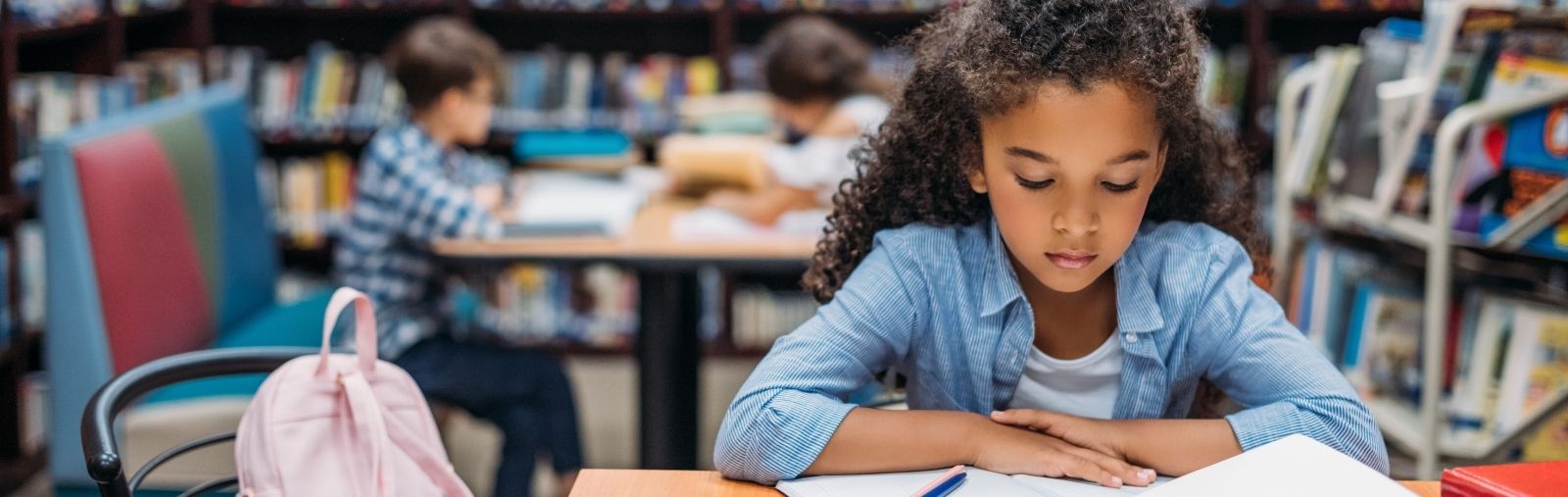 A girl reading a book at a desk in a library