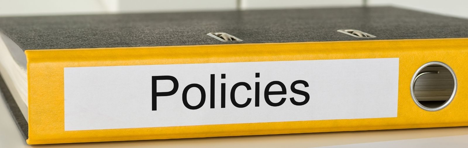 A binder labeled "Policies" on a table