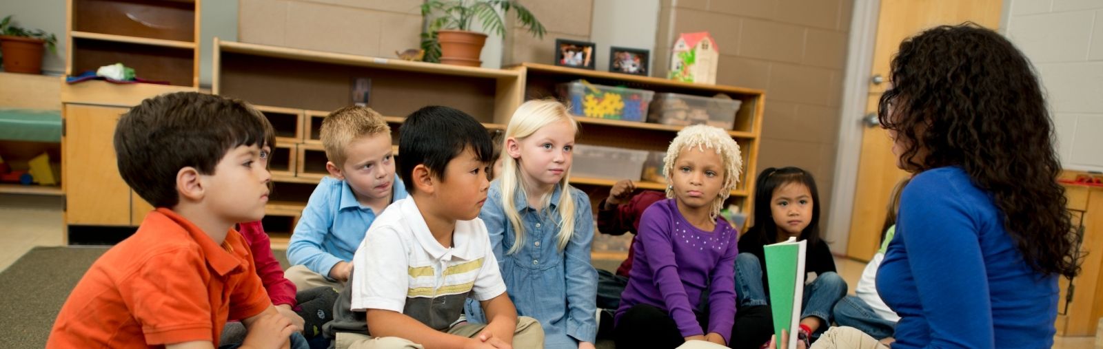 Children sitting and listening to a woman reading