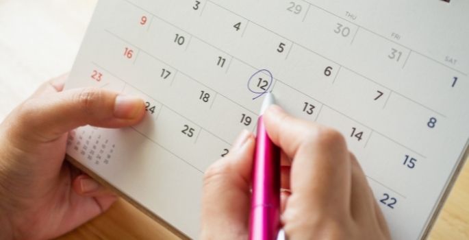 A hand circling a date on a calendar