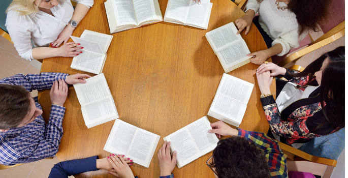 Overhead shot of a group of teens with books open on a table