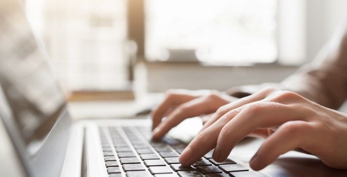 Hands typing on a laptop