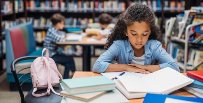 A girl reading a textbook in a library