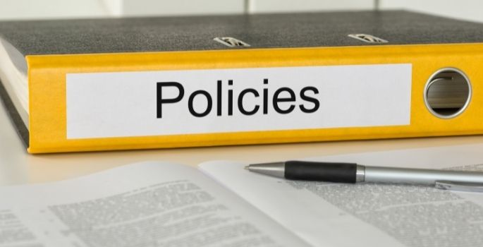 A binder labeled "Policies" sits on a table