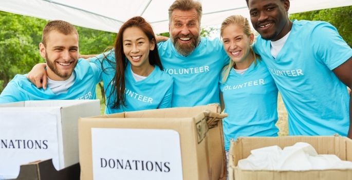 Five people in teal shirts saying "volunteer" behind a table