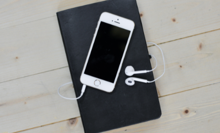 A phone with headphones resting on a black book