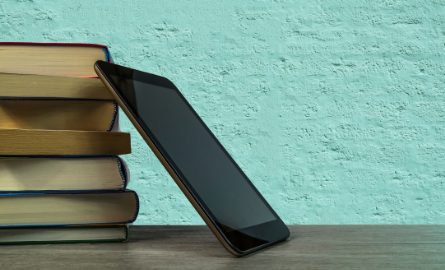 A tablet leaning against a stack of books