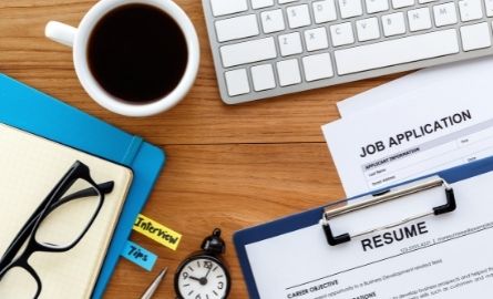 A resume, job application, and other papers on a desk