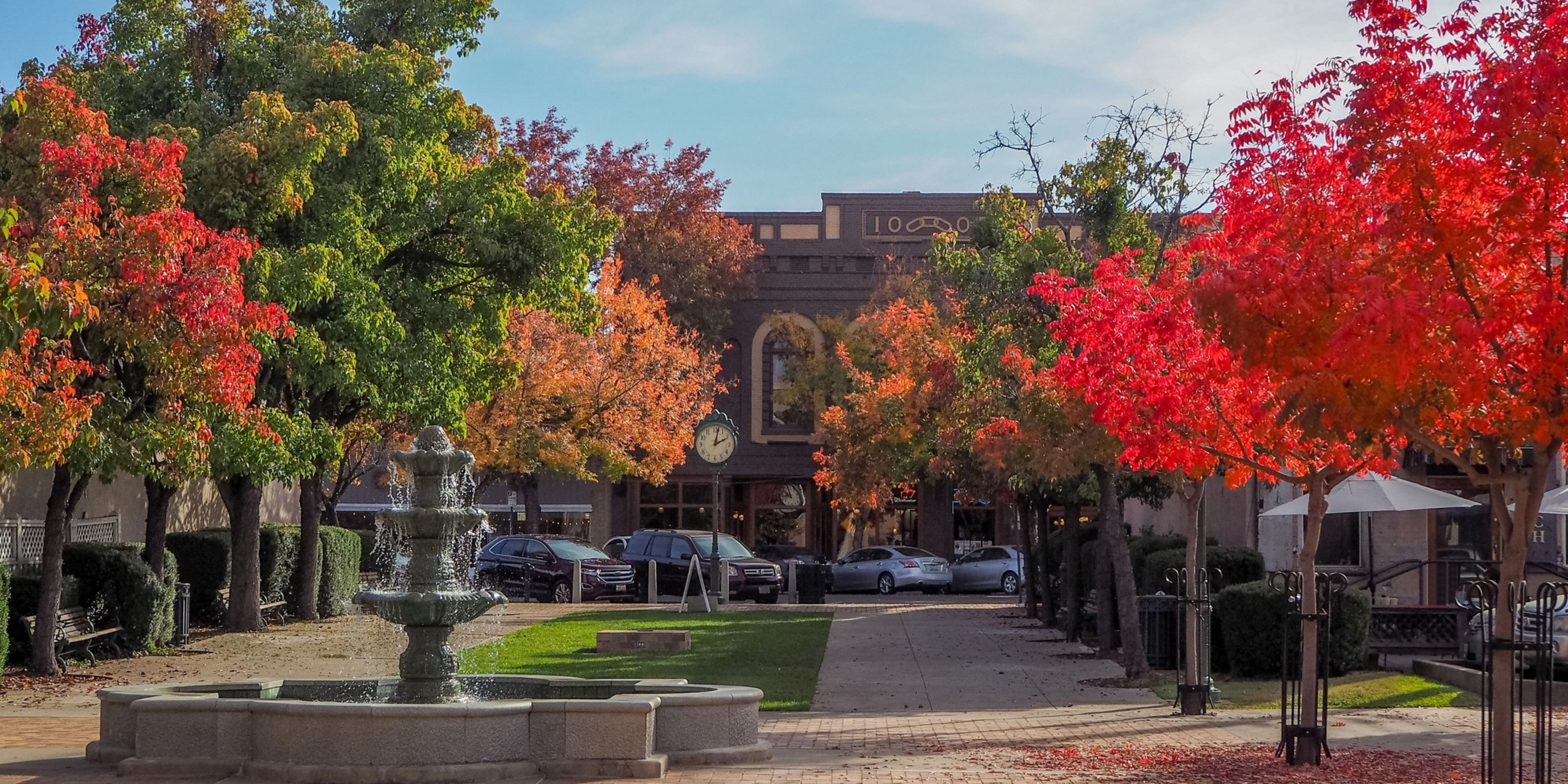 Water fountain and brick building with trees during autumn