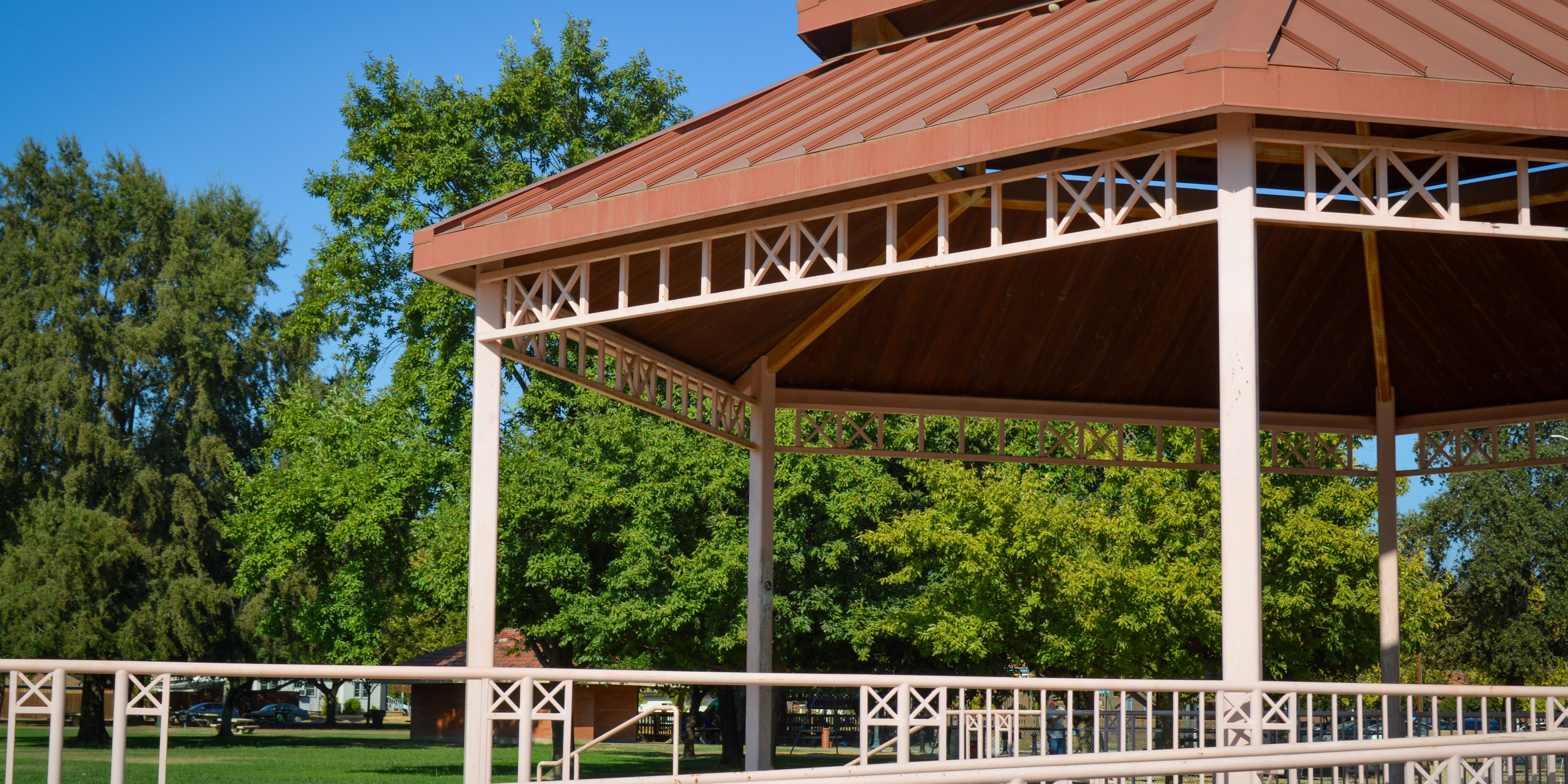 Red shade structure with blue skies and green trees