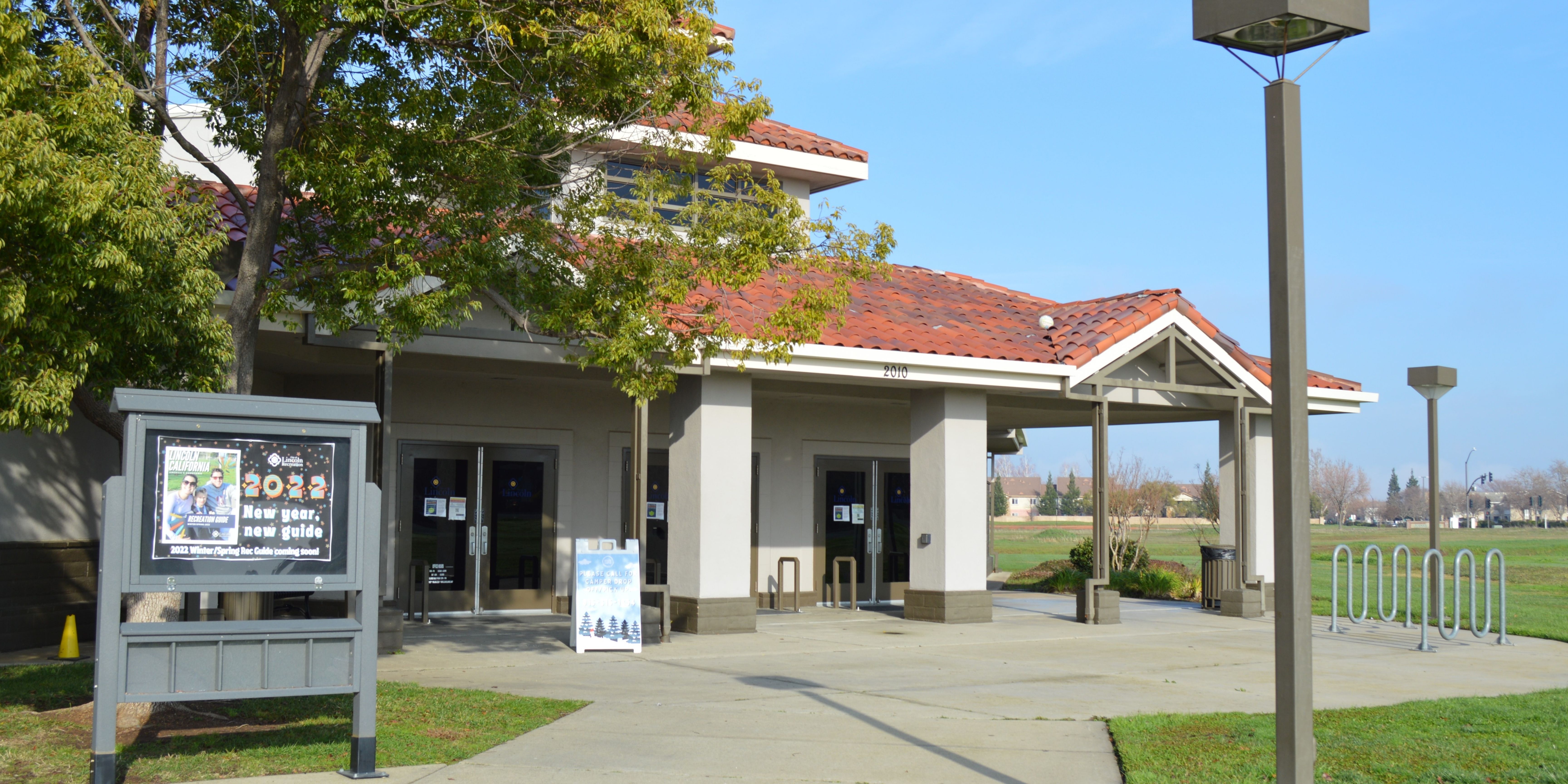 White building with red roof with blue sky and trees