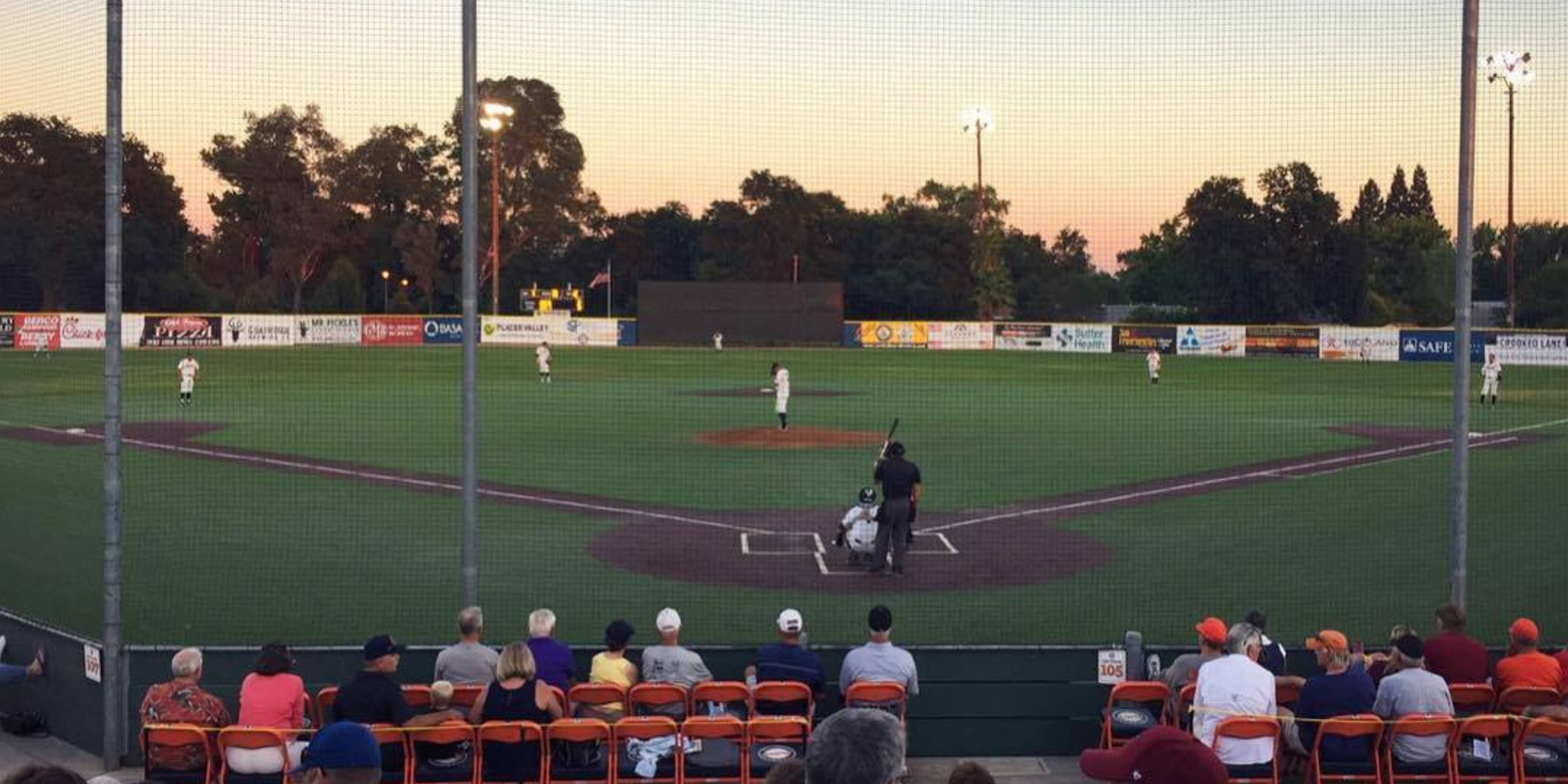 Green baseball field with sunset in background