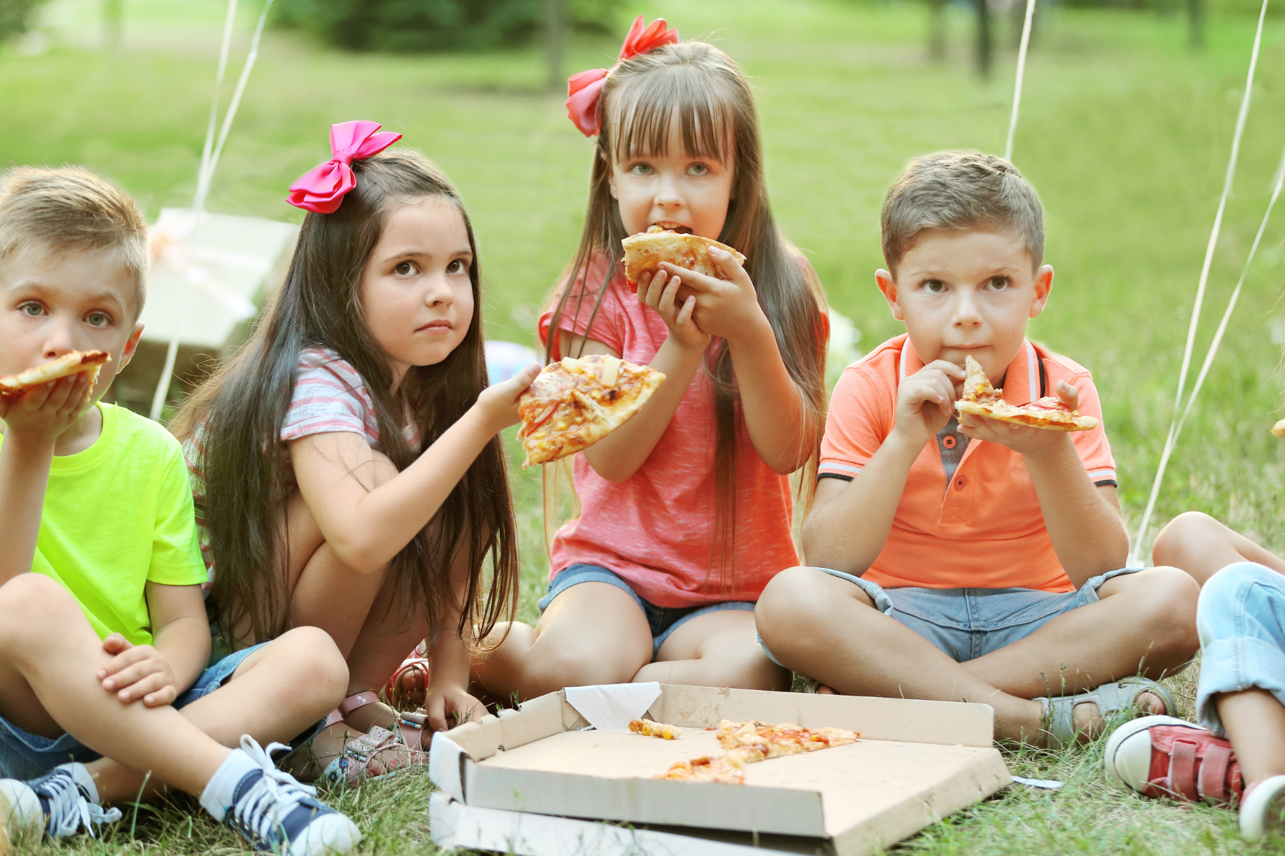 Kids eating pizza outside 