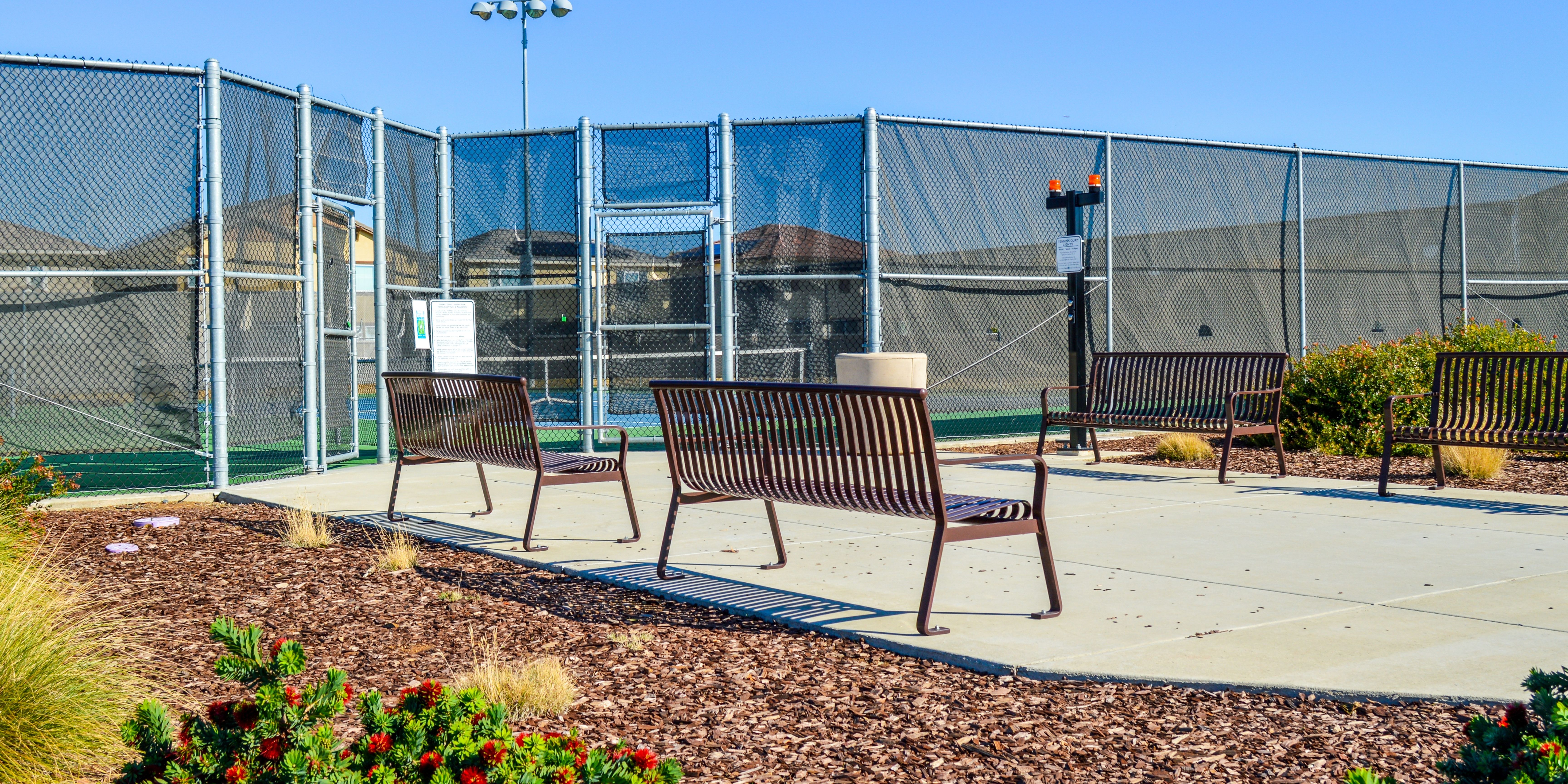 Park bench and tennis court on sunny day