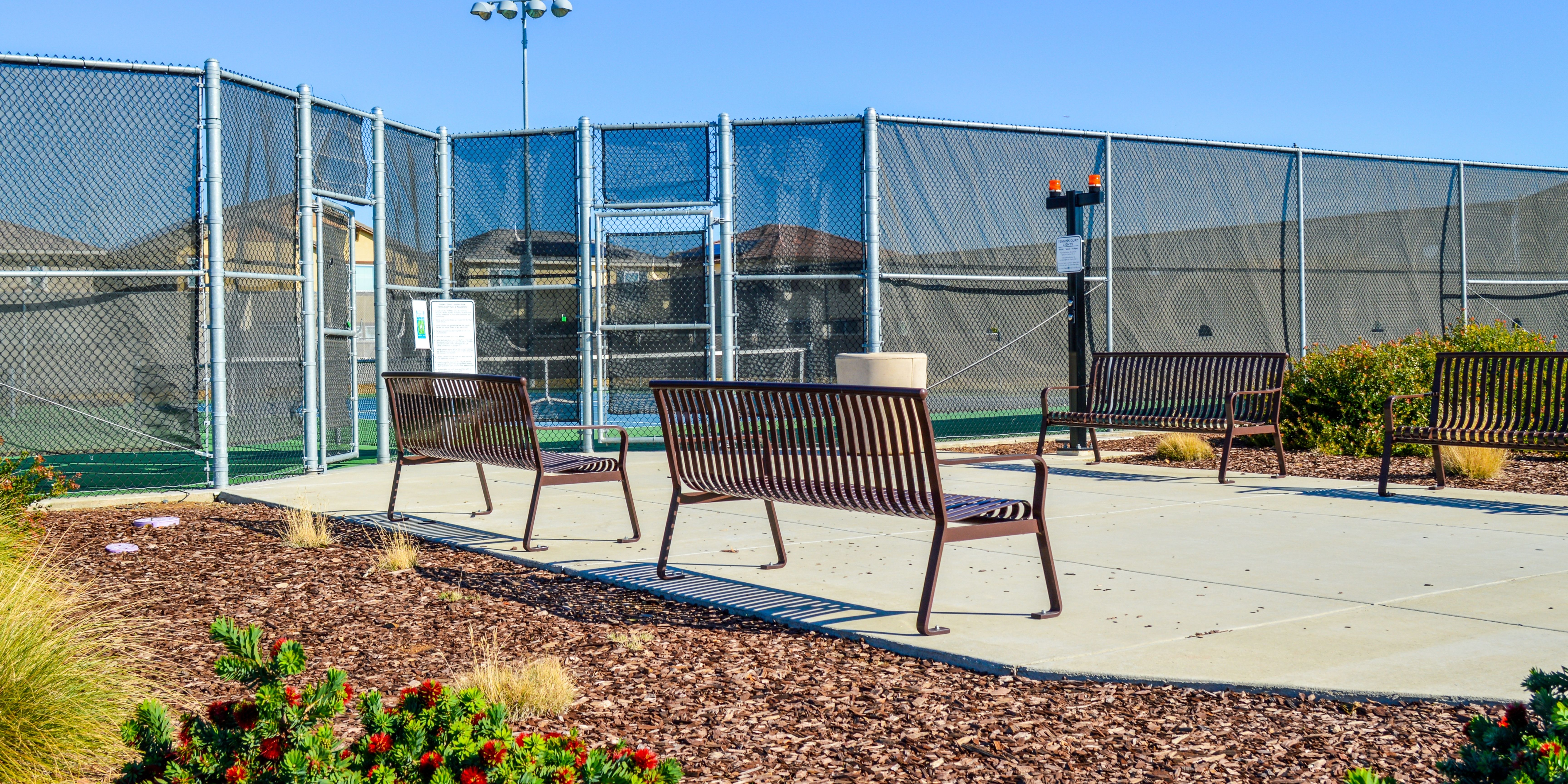 Benches with tennis court behind and blue skies