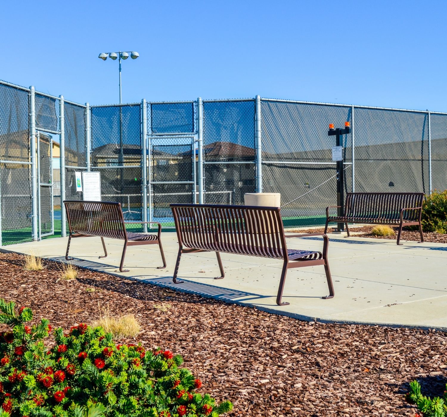 Metal benches with tennis courts on a sunny day with blue skies