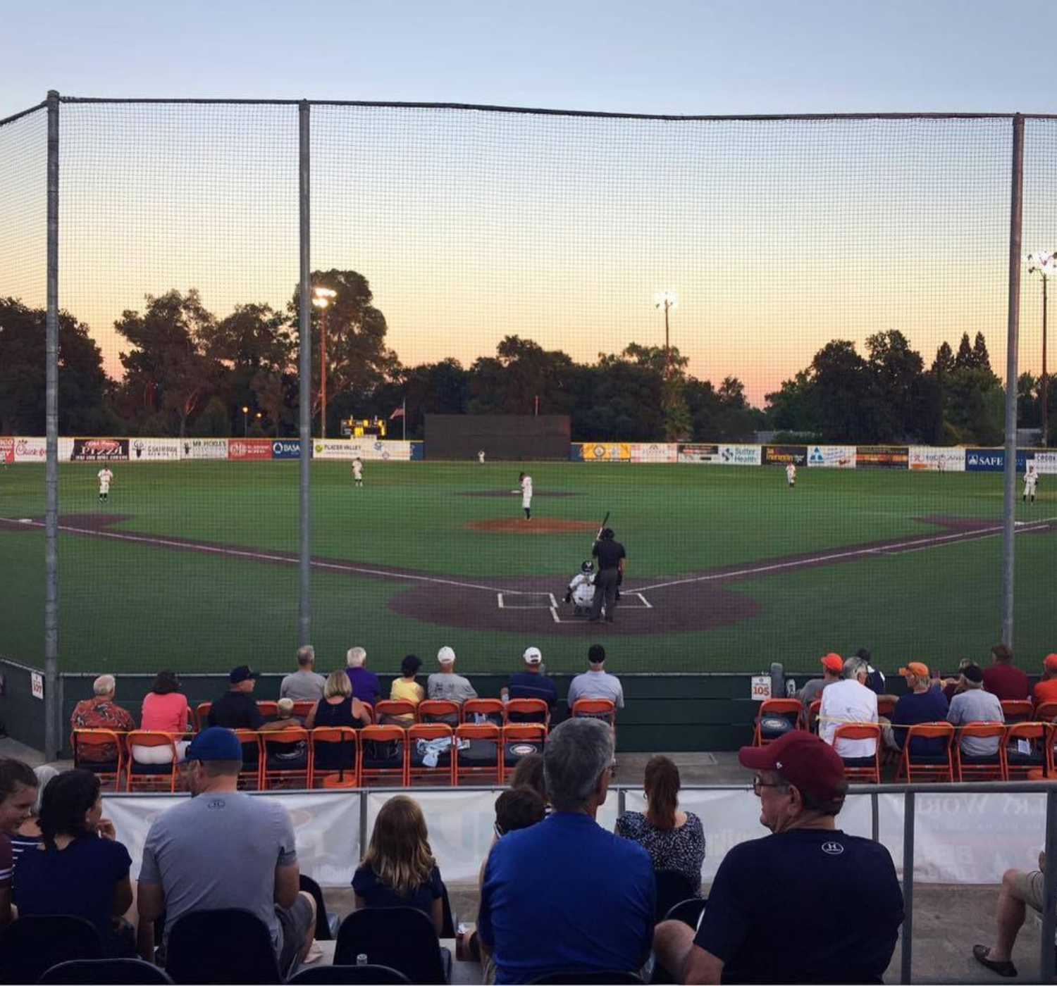 People sitting with baseball game and sunset