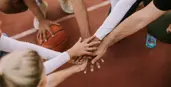 alt="all hands in on basketball court"