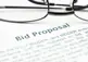 alt="Bid Proposal heading on paper with glasses."