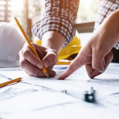 alt="plans being reviewed by 2 people holding pencils"
