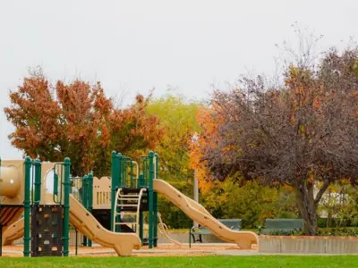 alt="Green playground with trees turning color in Autumn"