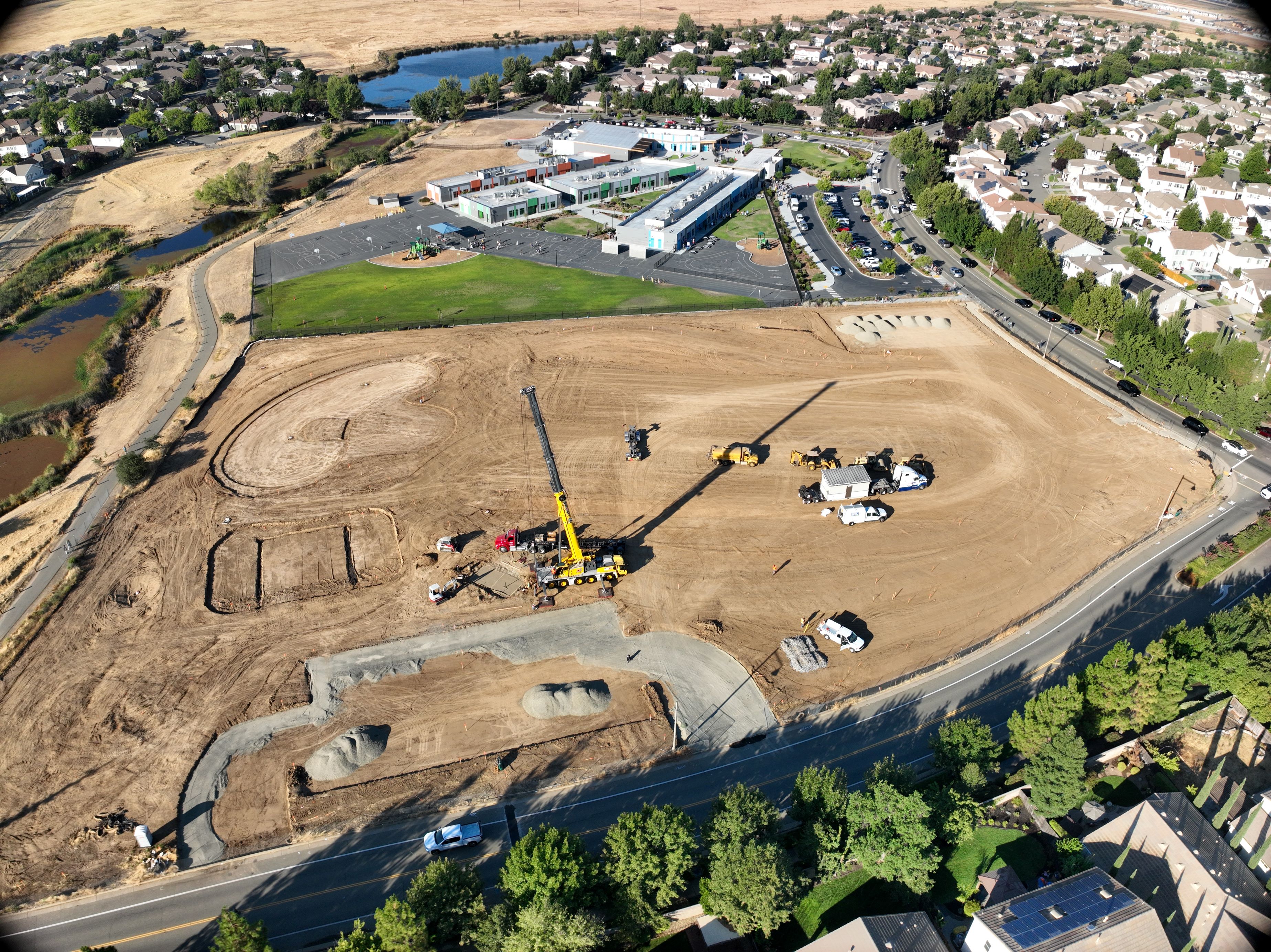 drone image of park during construction showing grading operations and restroom building being placed with a crane