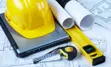 alt="Construction hat, computer and plans."