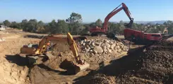 alt="backhoe construction vehicles working"