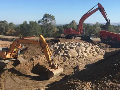 alt="backhoe construction vehicles working"